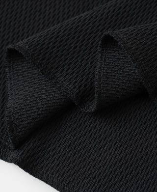 Black waffle knit thermal fabric close-up with subtle raised pattern