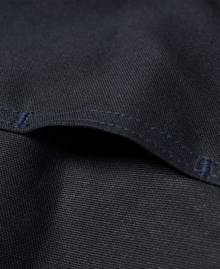 Navy canvas fabric close-up with stitched hem and curved pocket seam