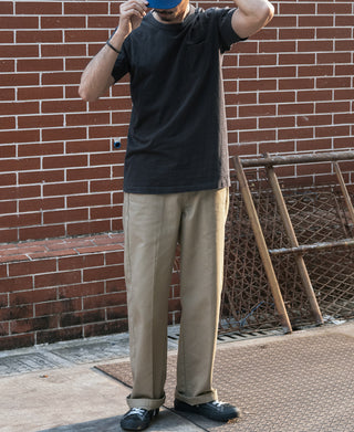 Men's black crew-neck T-shirt with chest pocket worn with light pants
