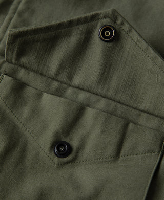 Olive field jacket pocket flap with snap button and reinforced stitching