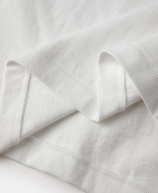 White tubular athletic t-shirt fabric with side hem stitching, close-up fold.