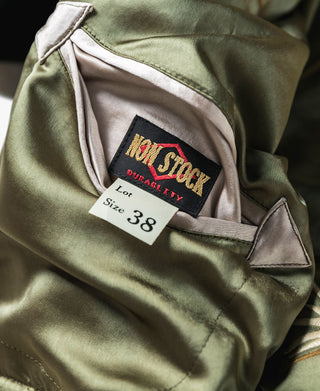 Olive green reversible jacket with light satin lining and size label at interior pocket.