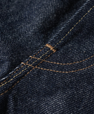 Dark blue denim jeans with orange-brown topstitching across a curved yoke seam