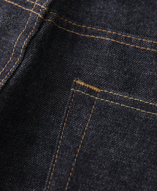 Close-up of indigo selvedge denim pocket seam with orange-gold stitching