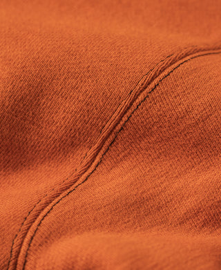 Orange sweatshirt fabric with stitched seam along dark V-inset panel edge.
