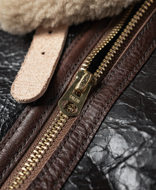 Close-up of front zipper and leather pull tab on dark brown flight jacket