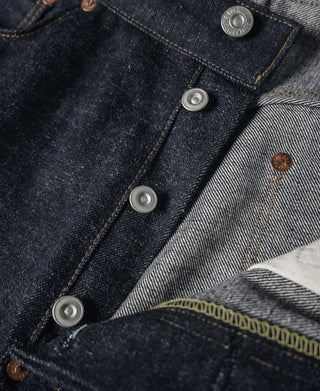 Dark indigo denim jeans close-up of front fly and metal button row