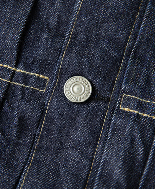 Indigo denim jacket close-up with round metal button and contrast stitching