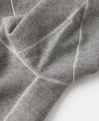 Gray sweater with ribbed hem and crossover sleeve/side seams.
