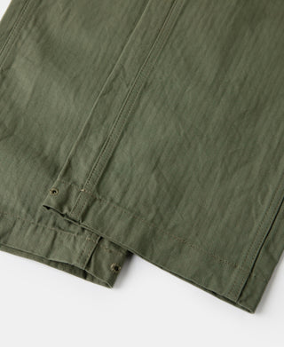 Olive fatigue trousers close-up of side seam and straight hem edge.
