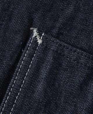 Indigo denim jacket corner seam with bar-tack stitching and topstitch lines
