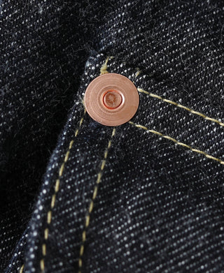 Indigo denim jacket seam detail with copper button and yellow topstitching