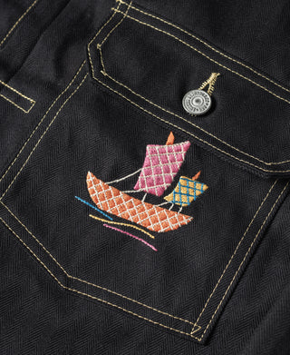 Black chest pocket with embroidered sailboat and fish designs, edged in gold trim