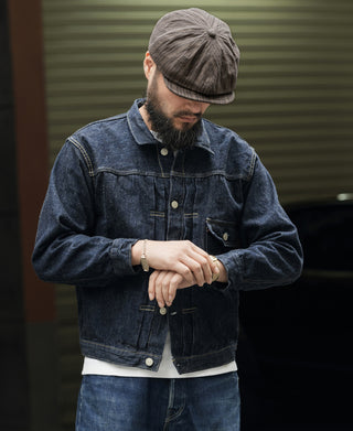 Dark gray striped newsboy cap worn by a man with denim jacket