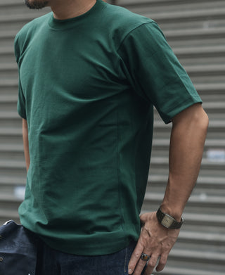 Green crew-neck short-sleeve T-shirt worn by a model, partial close-up on chest.