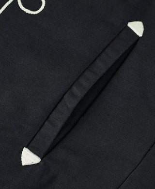 Black jacket hem detail with diagonal sleeve vent and matching dark trim