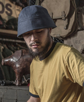 Navy Dixie Cup cap worn by a man, side profile in yellow shirt