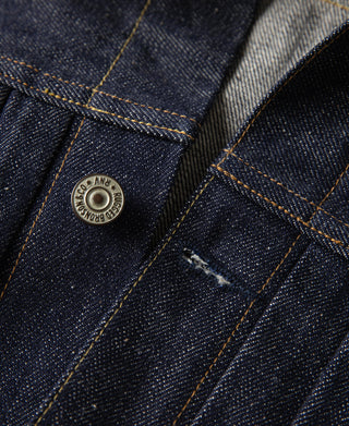 Indigo denim jacket pocket area with metal button and stitched seam