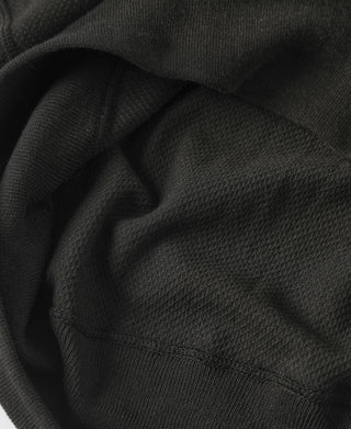 Black waffle-knit t-shirt fabric close-up with ribbed hem and sleeve