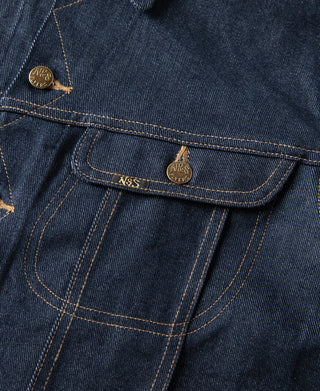 Indigo denim jacket side pocket close-up with brass button and stitched seams.