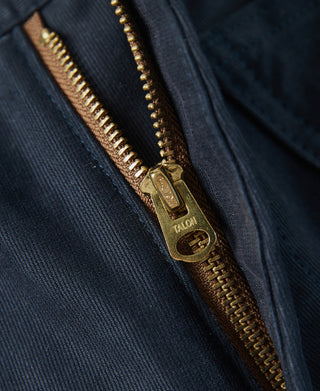 Navy deck pants zip fly close-up with brass-toned zipper pull and teeth.