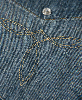 Blue denim western yoke seam with tan contrast stitching and metal snap