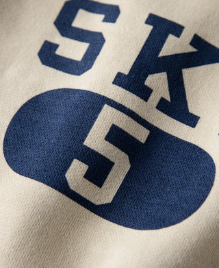 Cream sweatshirt close-up of blue “SKI 5” graphic print