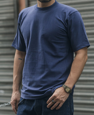 Navy crew-neck T-shirt worn on a person, short sleeves and drape across chest