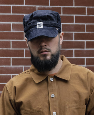 Indigo denim engineer cap with front patch and curved brim, on model
