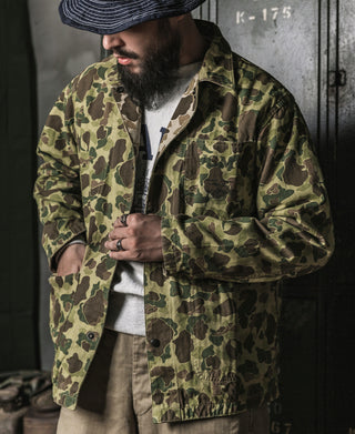 Camouflage duck hunter camo jacket worn with dark shirt, button front and chest pocket