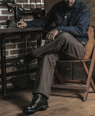 Brown pinstripe pants with front pleats, straight legs, and cuffed hem