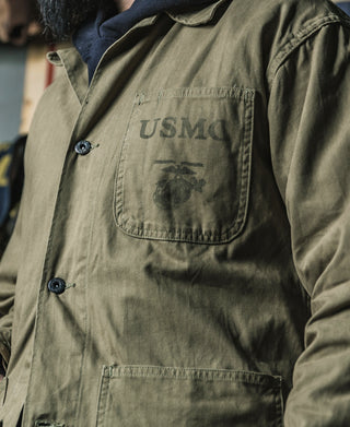 Olive utility jacket front close-up with USMC chest pocket and button placket