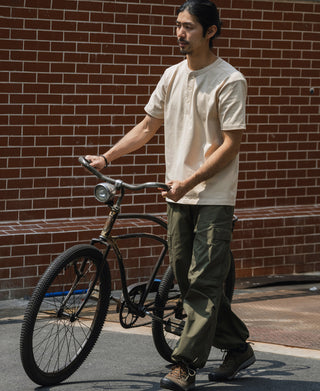 Men’s apricot short-sleeve henley T-shirt with three-button front, worn with pants