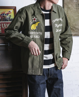 Olive bomber jacket with chest emblem and cursive script on the lining