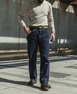 Dark indigo selvedge denim jeans on person, relaxed straight leg and cuffed hem