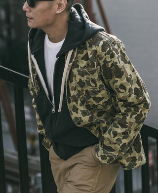 Camouflage duck hunter camo jacket worn on model, front pockets and hood visible