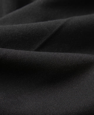 Black trouser fabric close-up with textured weave and fine seam stitching