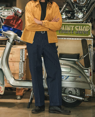 Navy pinstripe work pants on model; pleated waist and wide straight leg