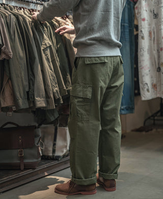 Olive fatigue pants with cuffed hem and cargo pocket, worn, full view