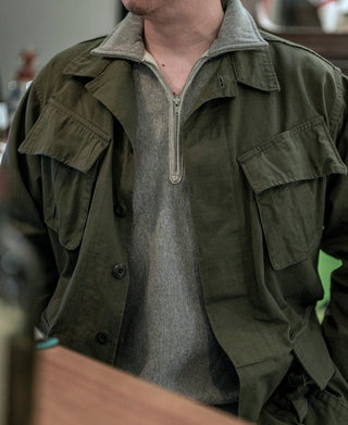 Olive jacket with high collar, front zipper, and flap pockets on the chest
