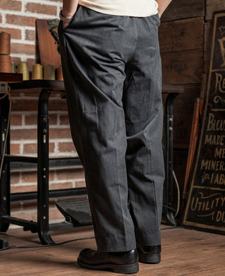 Dark gray double-pleated chino trousers, side view with tapered cuffed hem