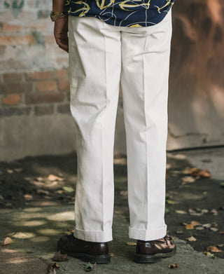 White cotton twill trousers with crease lines and straight, slightly tapered legs