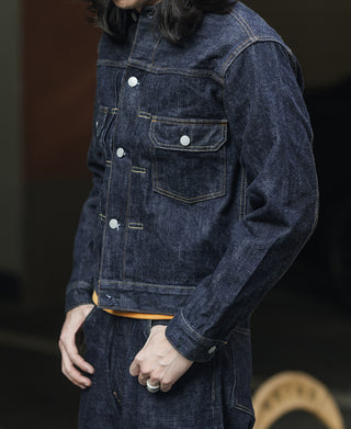 Indigo denim jacket with four front pockets, button cuffs, and metal snap closure