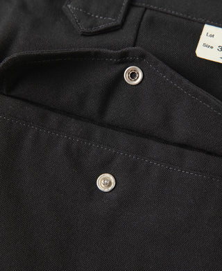 Black trousers close-up of flap pocket with silver snap buttons and stitching