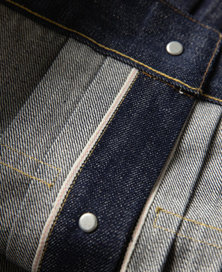Indigo selvedge denim jacket placket with contrast stitching and two metal snaps