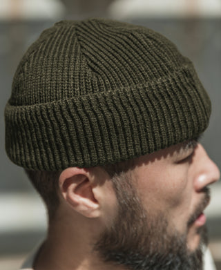 Olive knit watch cap on model, side profile showing ribbing