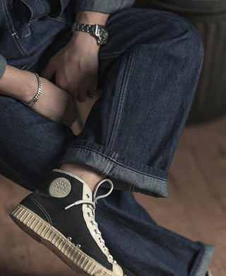Close-up of indigo denim cuff and lace-up shoe with contrast stitching