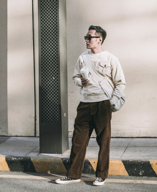 Apricot crewneck pocket sweatshirt worn with dark pants and sneakers