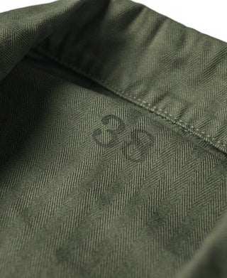 Olive green HBT jacket fabric close-up with herringbone texture near collar