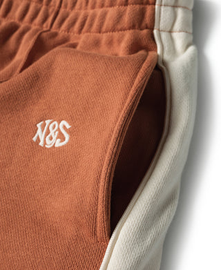 Orange sweatpants pocket area with small white "YES" logo and light-blue contrast trim